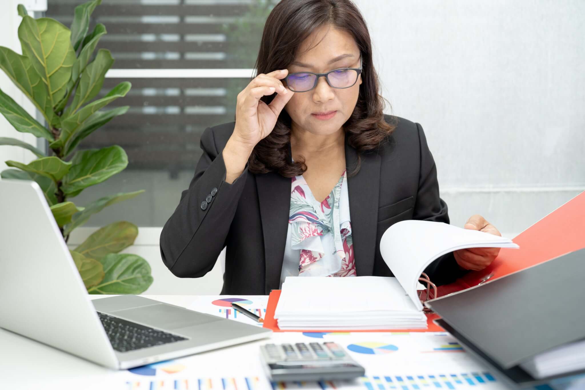 a woman sitting at a desk with a laptop and a book