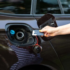a hand holding a card to a gas tank
