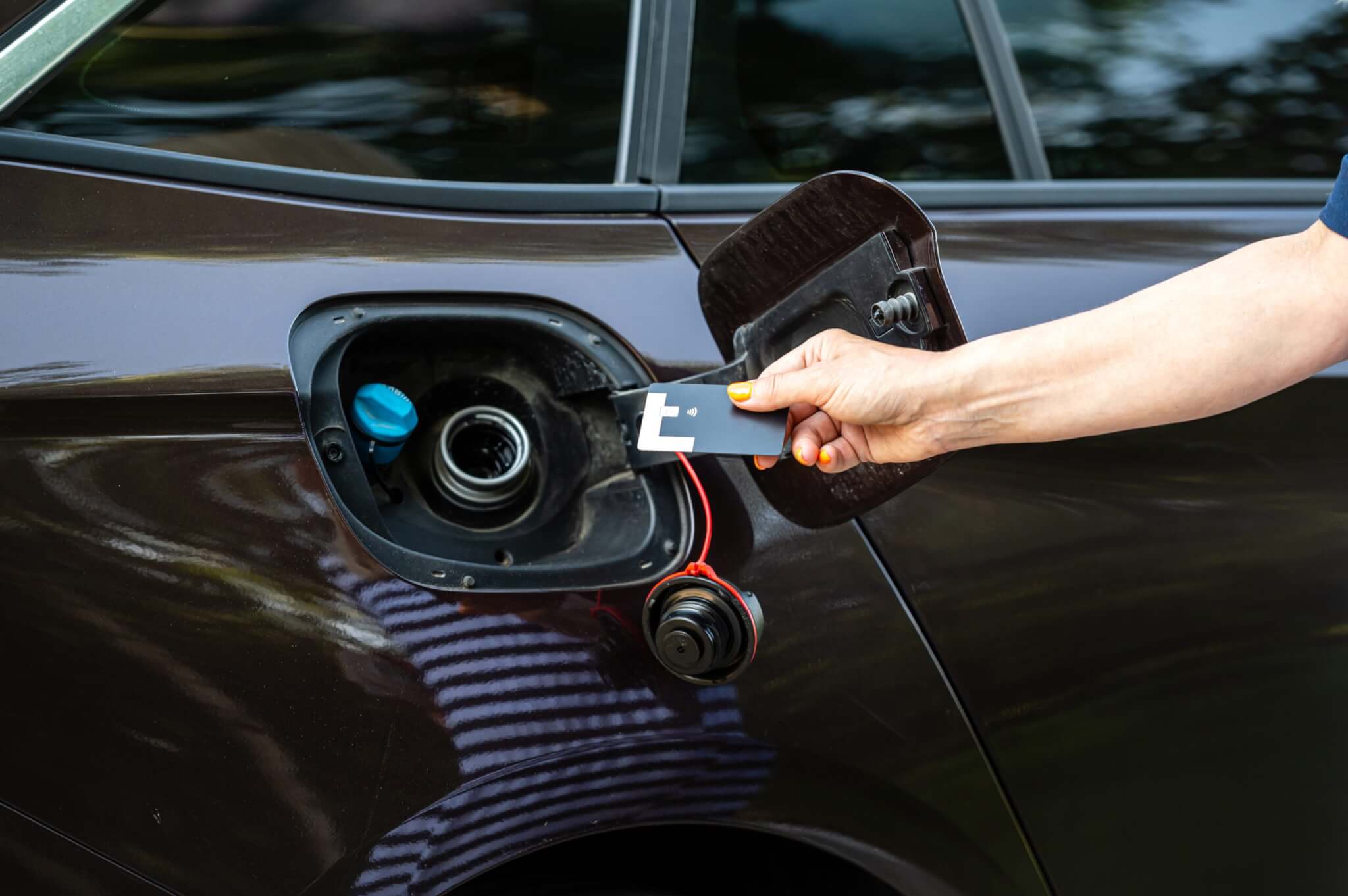 a hand holding a card to a gas tank